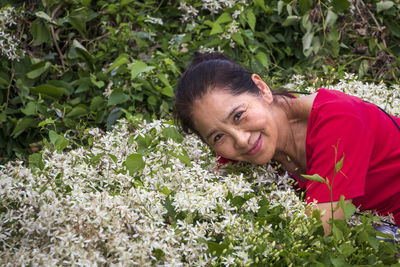 Portrait of smiling woman by flowering plants
