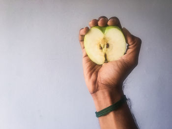 Hand holding apple against white background