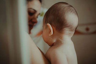 Close-up of shirtless mother and daughter at home