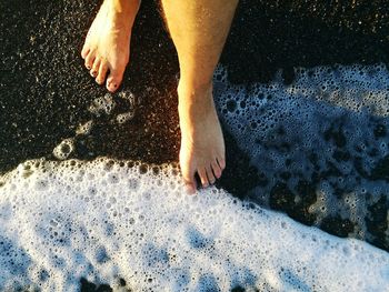 Low section of man standing on shore at beach