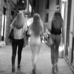 Rear view of women walking on street in city