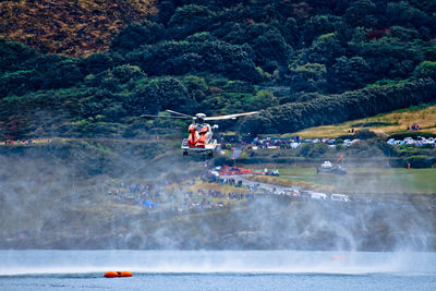 People on boat in river against mountains