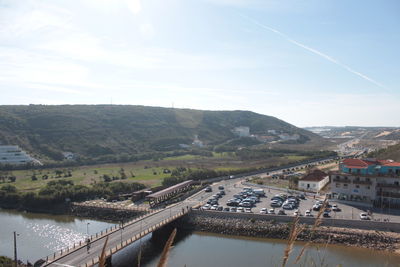 Aerial view of bridge over river by city against sky