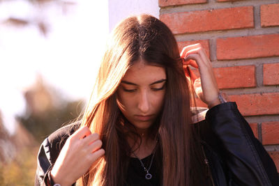 Beautiful woman with hand in hair against wall