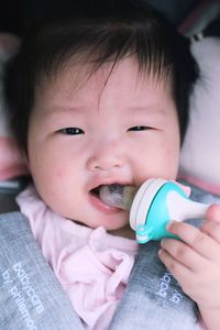 Close-up portrait of cute baby girl with pacifier lying on bed at home