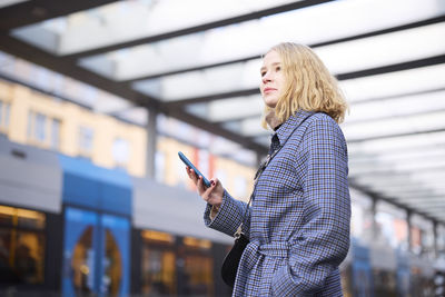 Woman using cell phone at tram stop