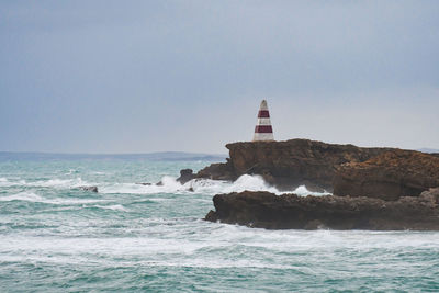 Lighthouse by sea against clear sky