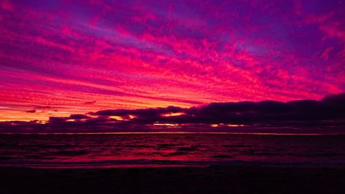 Scenic view of sea against dramatic sky during sunset