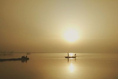 Boat sailing in sea at sunset