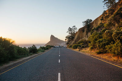 Road leading towards mountain against clear sky