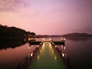 Pier over lake against sky at sunset