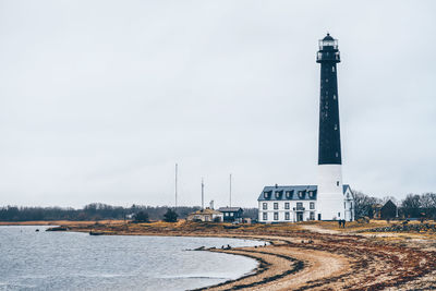 Lighthouse amidst buildings against sky