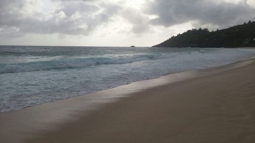 Scenic view of beach against cloudy sky