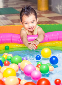 Portrait of smiling girl with colorful balls in wading pool