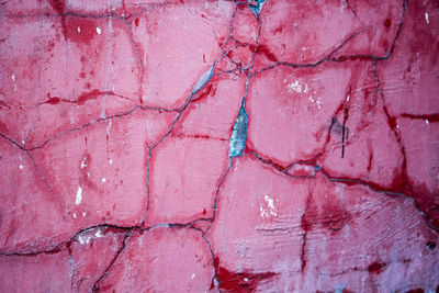 Cracks on a pink wall closeup