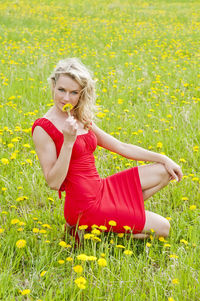 Full length of woman wearing red flower on field