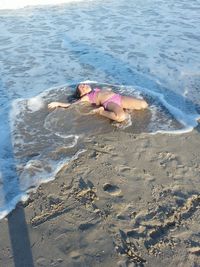 Happy girl in bikini lying on shore