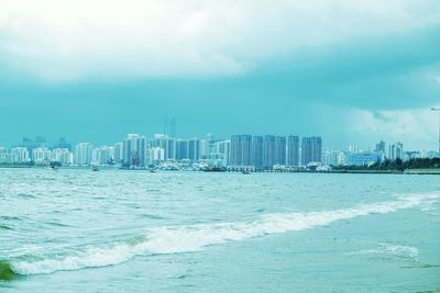 City at waterfront against cloudy sky