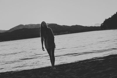 Full length of woman standing by river against clear sky