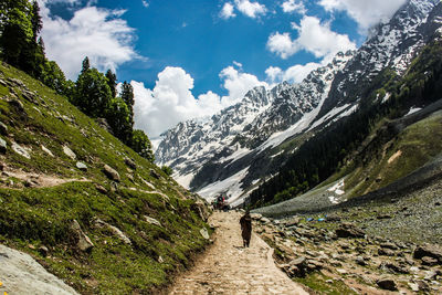 Rear view of man walking on mountain against sky