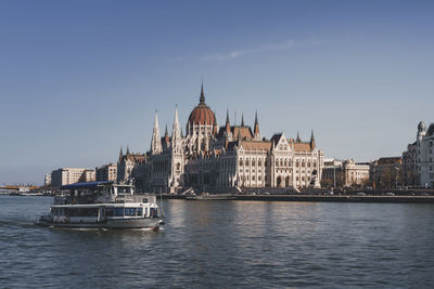 Buildings by river against clear sky