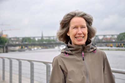 Portrait of smiling woman standing against railing