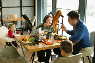 High angle view of father with children eating breakfast at restaurant