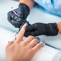 Close-up of woman doing nail art of customer at table