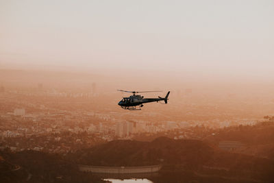 Helicopter flying over city during sunset