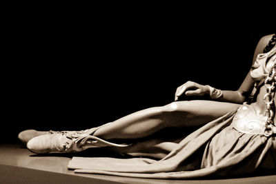 Low section of woman sitting against black background