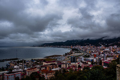 High angle view of townscape by sea against storm clouds