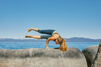 Young woman practicing yoga on lake tahoe in northern california.