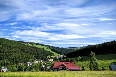 Houses on field against cloudy sky