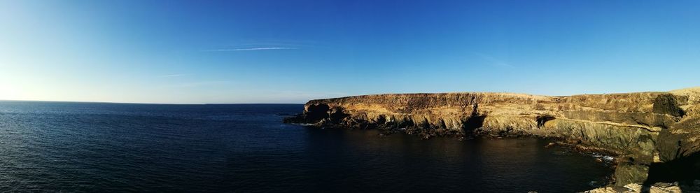 Scenic view of rock formation in sea against blue sky