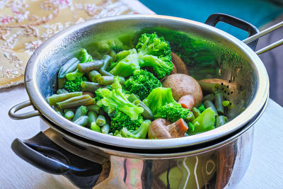 Boiled green vegetables in stainless steel colander - full-frame closeup