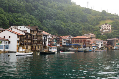 Houses by river and buildings against mountain