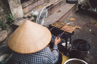 Rear view of man preparing food on street