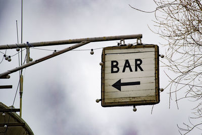 Low angle view of bar sign against sky