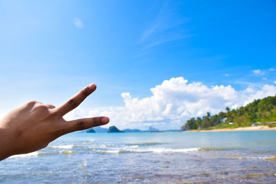 Cropped hand showing peace sign at beach