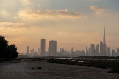 Modern buildings in city against sky during sunset