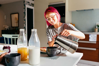 Portrait of young woman drinking water at home