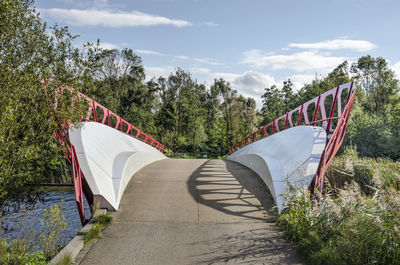 Modern pedestrian bridge amidst trees against sky