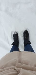 Low section of person standing on snow covered land