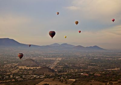 High angle view of hot air balloons flying over landscape