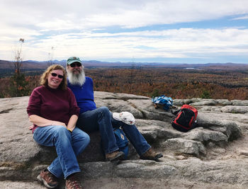 Portrait of woman sitting on rock against sky