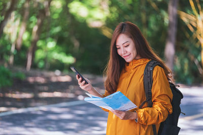 Portrait of young woman standing against trees