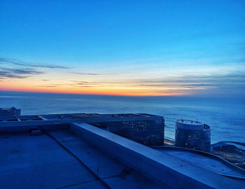High angle view of sea and buildings against sky at sunset