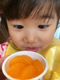 Close-up of cute girl looking at oranges in bowl