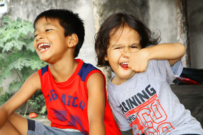 Portrait of smiling girl showing thumbs while sitting by happy brother