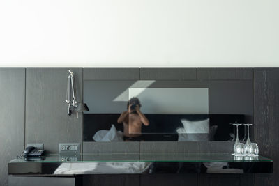 Rear view of shirtless man sitting in bathroom